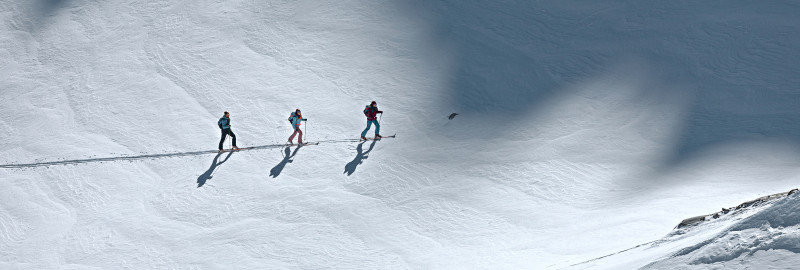 Ski tourers making tracks through a pristine snow-covered cirque