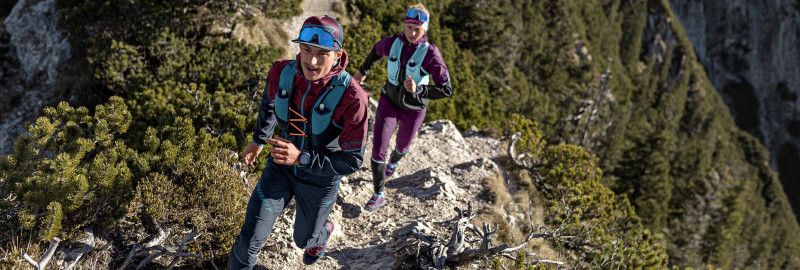 Zwei Trail Läufer:innen im Sonnenuntergang am Berg